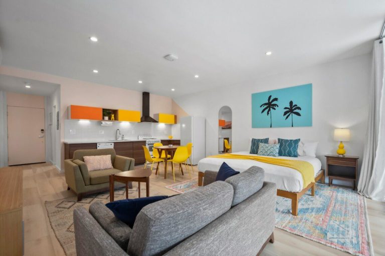 Yellow condo living area with king bed and palm tree art