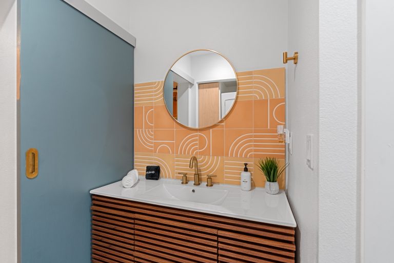 Blue Condo bathroom vanity with round mirror and arched tile