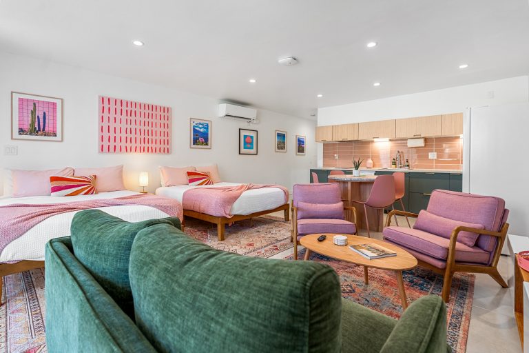 Pink Condo living area with green sofa and two queen beds