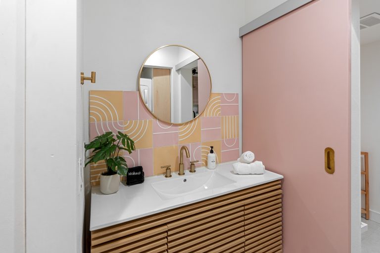 Pink Condo bathroom vanity with round mirror and pink door