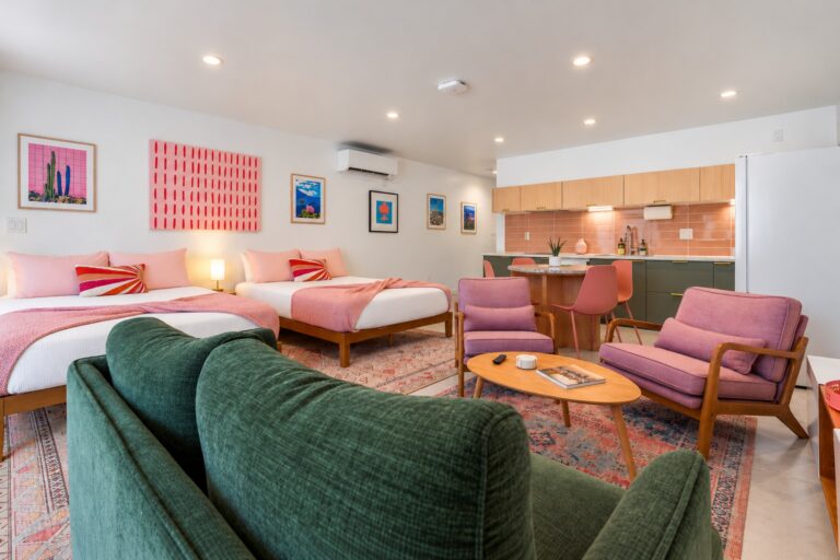 Pink condo living room with green sofa and two queen beds